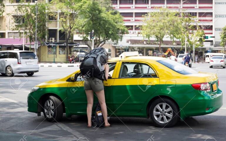 Tourist woman with backpack talking to taxi driver to get directions